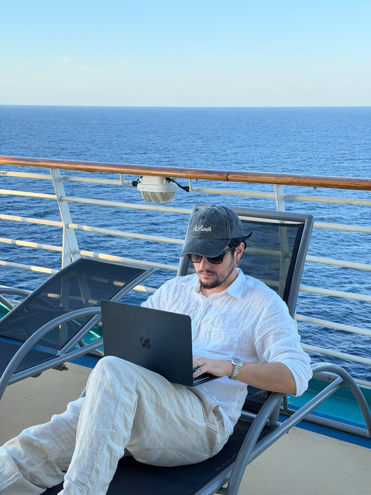 André Furtado, fundador da HEYJOB, trabalhando no notebook com o mar ao fundo
